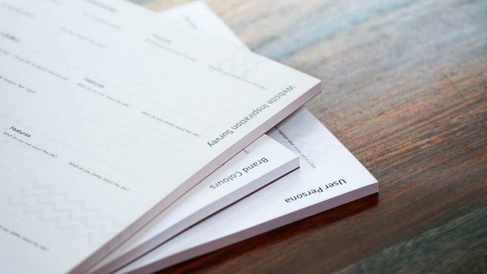 a stack of papers sitting on top of a wooden table