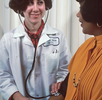 a woman in a doctor's coat talking to another woman