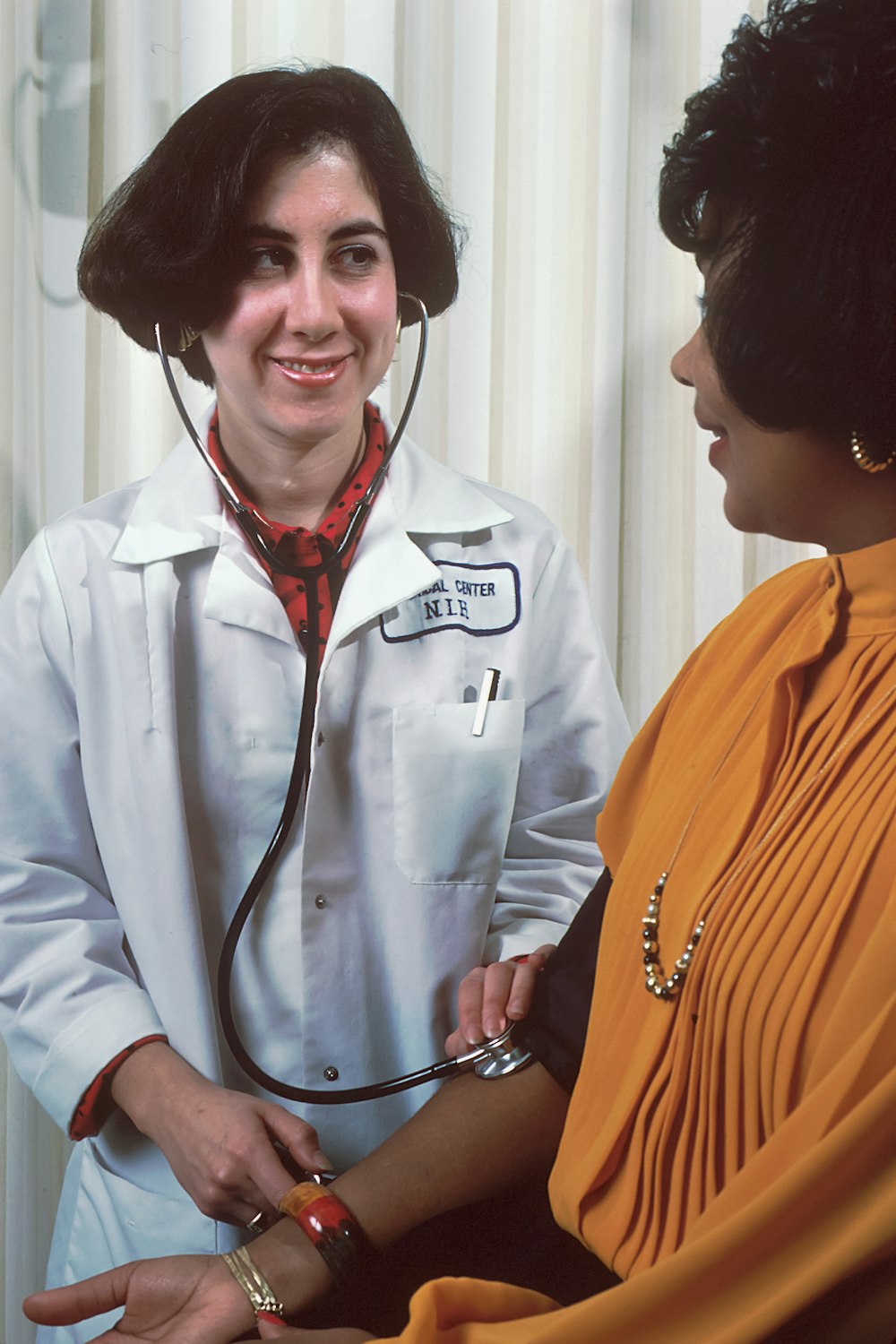 a woman in a doctor's coat talking to another woman