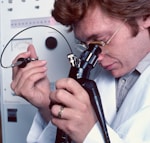 a man in a lab coat looking through a microscope