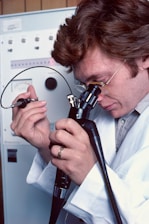 a man in a lab coat looking through a microscope