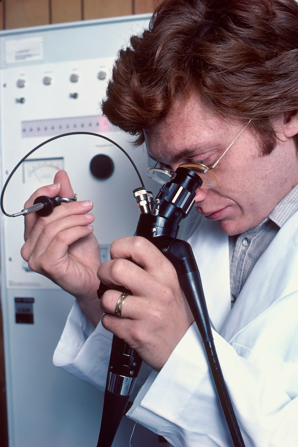 Ein Mann im Laborkittel schaut durch ein Mikroskop