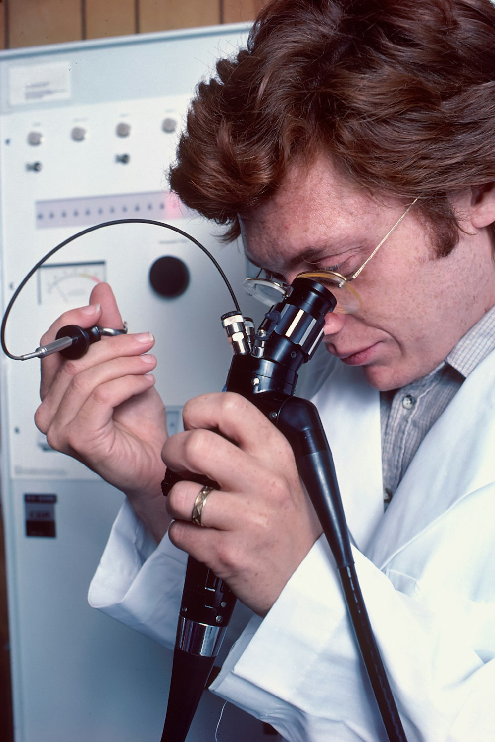 a man in a lab coat looking through a microscope