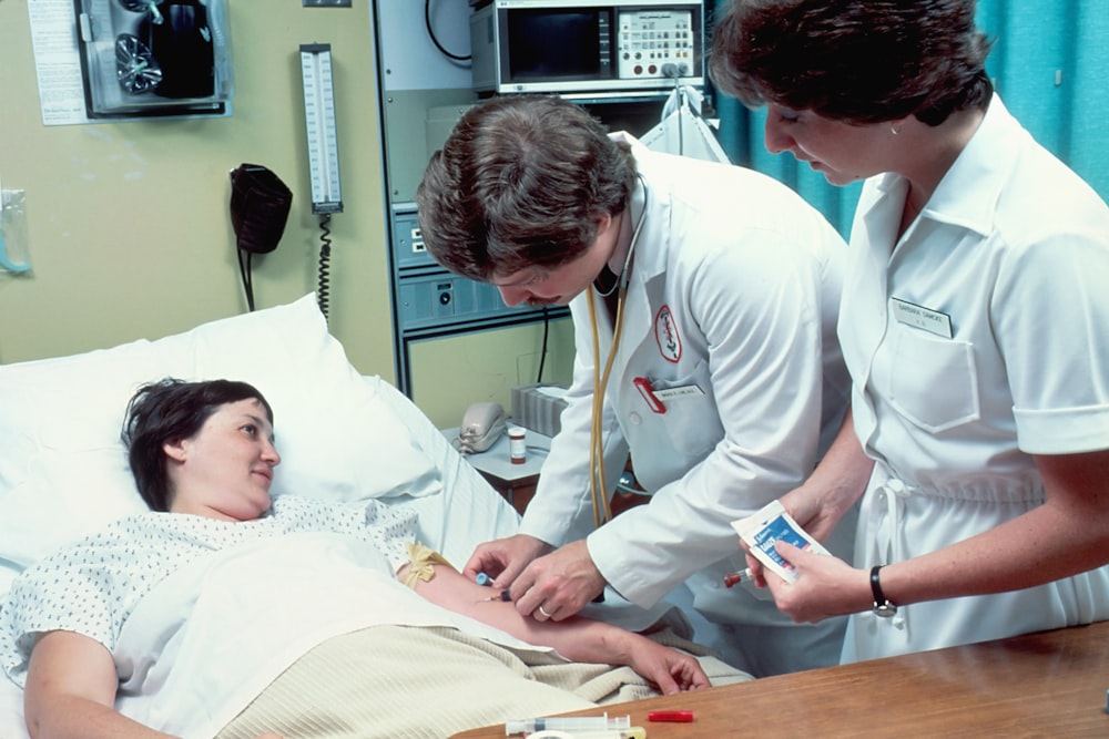 uma mulher deitada em uma cama de hospital ao lado de um homem