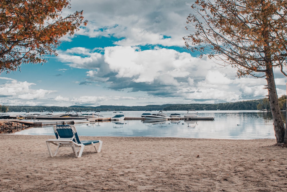 une chaise assise sur une plage à côté d’un plan d’eau