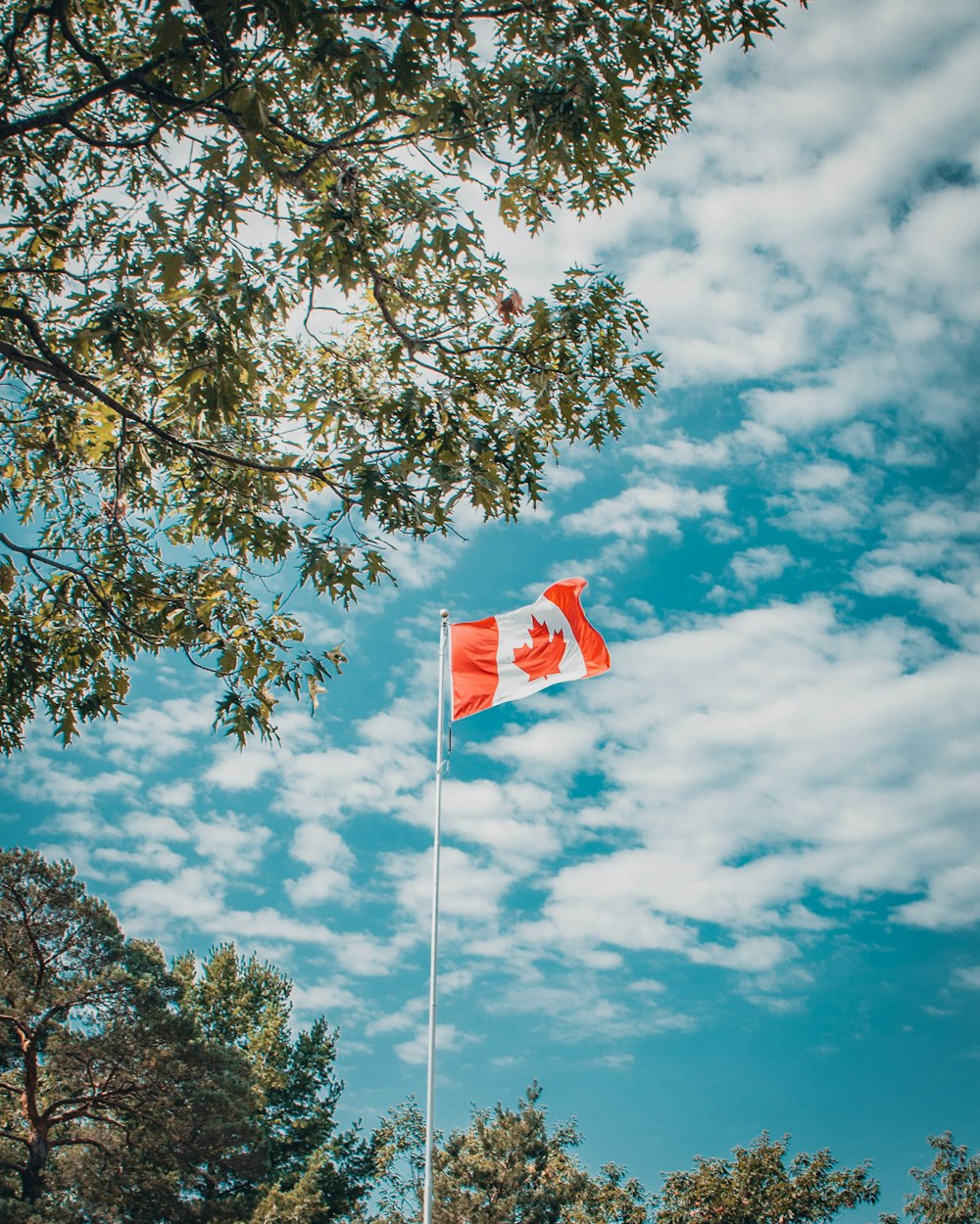 a canadian flag flying high in the sky