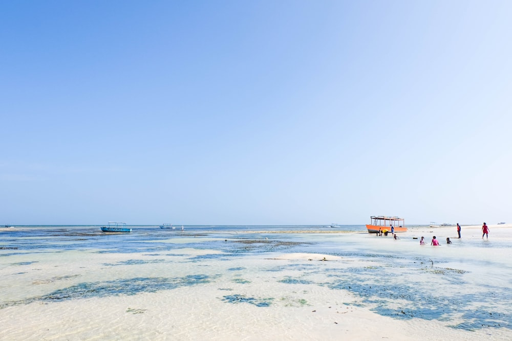 a group of people standing on top of a sandy beach