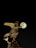 A bronze statue of an angelic figure with wings holds a glowing orb, illuminated against a dark night sky. Below, architectural details suggest a structure with small spires, partially visible in silhouette.