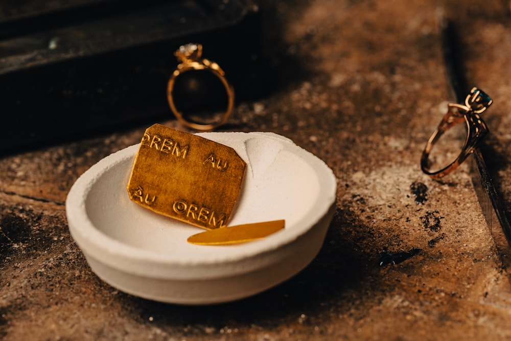 a couple of gold rings sitting on top of a white bowl