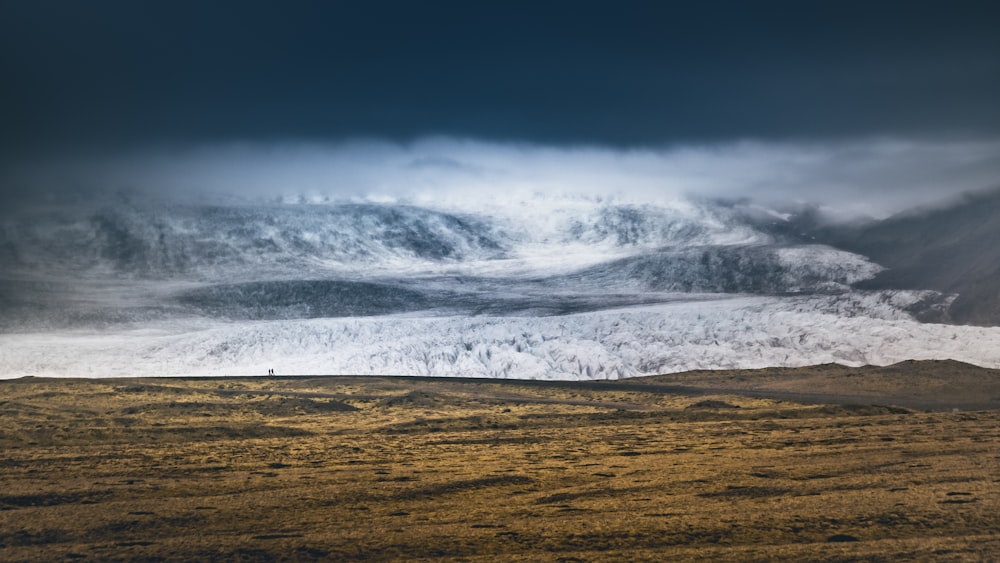 a large mountain covered in snow under a cloudy sky