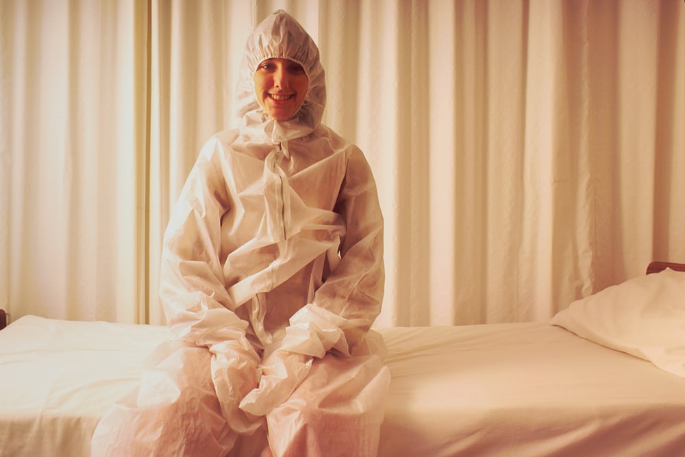 a person sitting on a bed in a plastic suit