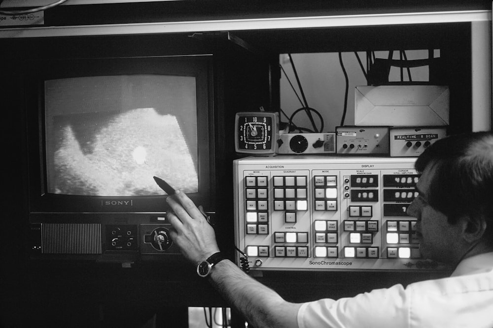 a black and white photo of a man looking at a television