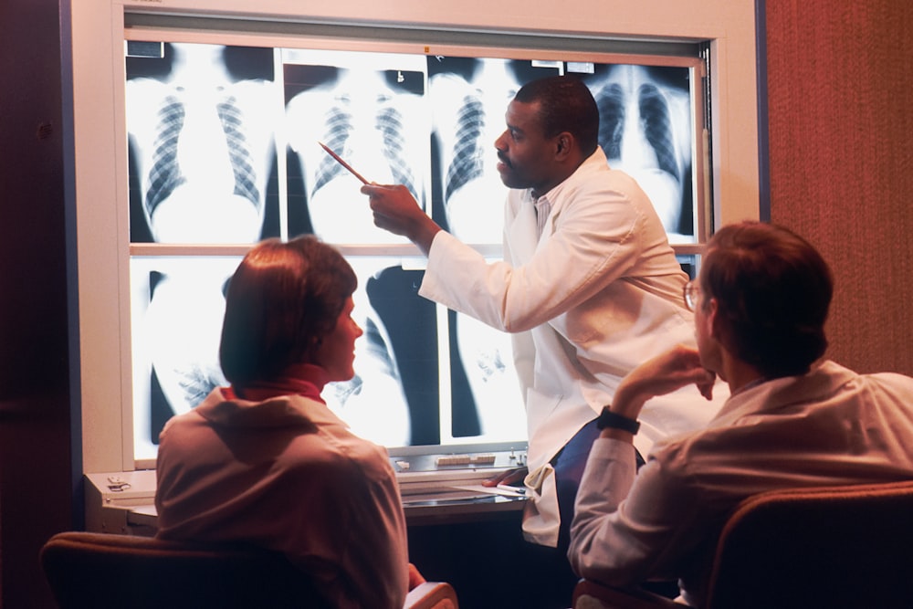 흰색 실험실 코트를 입은 남자가 엑스레이를 가리키고 있다