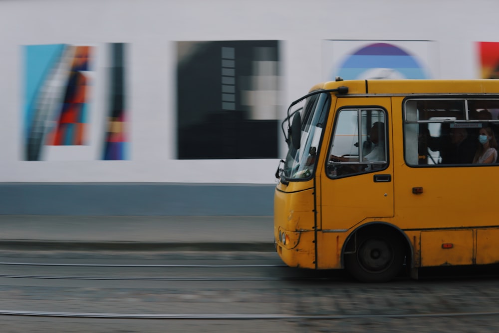 a yellow bus driving down a street next to a building