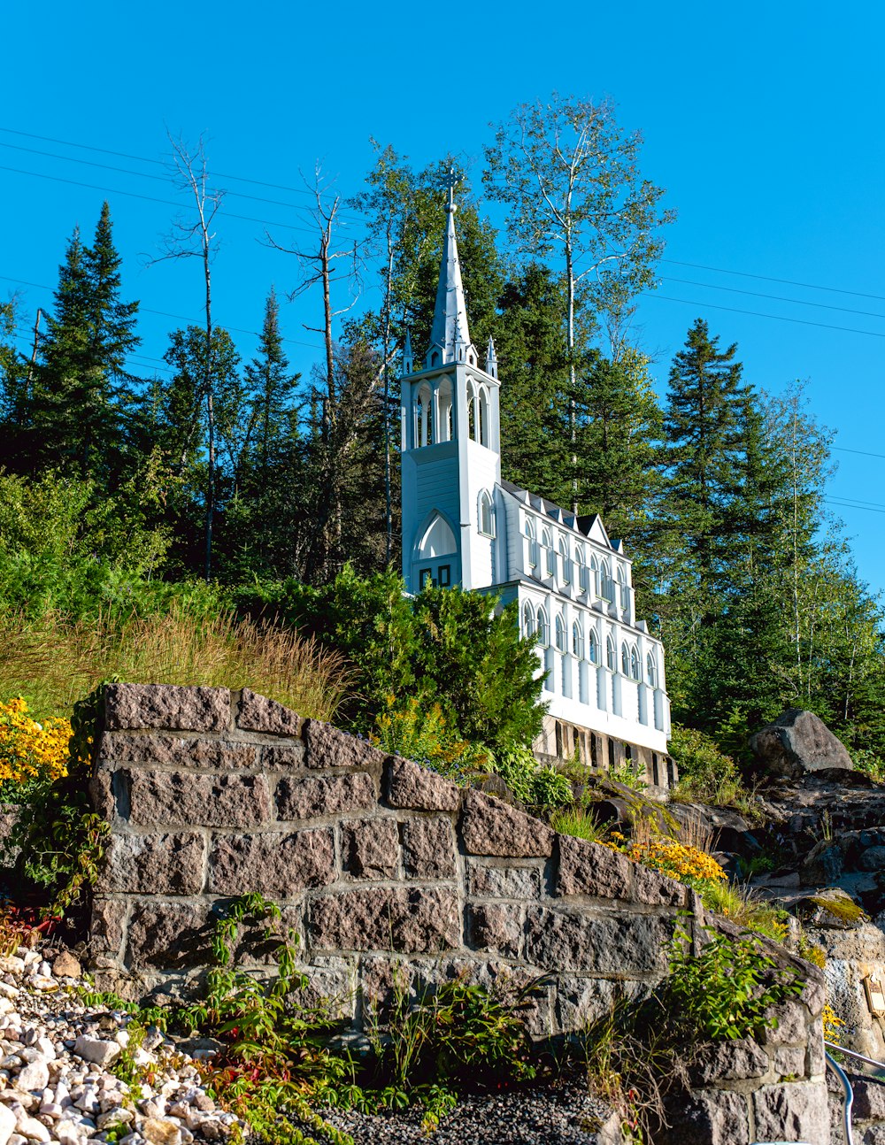 a white church on a hill with trees in the background