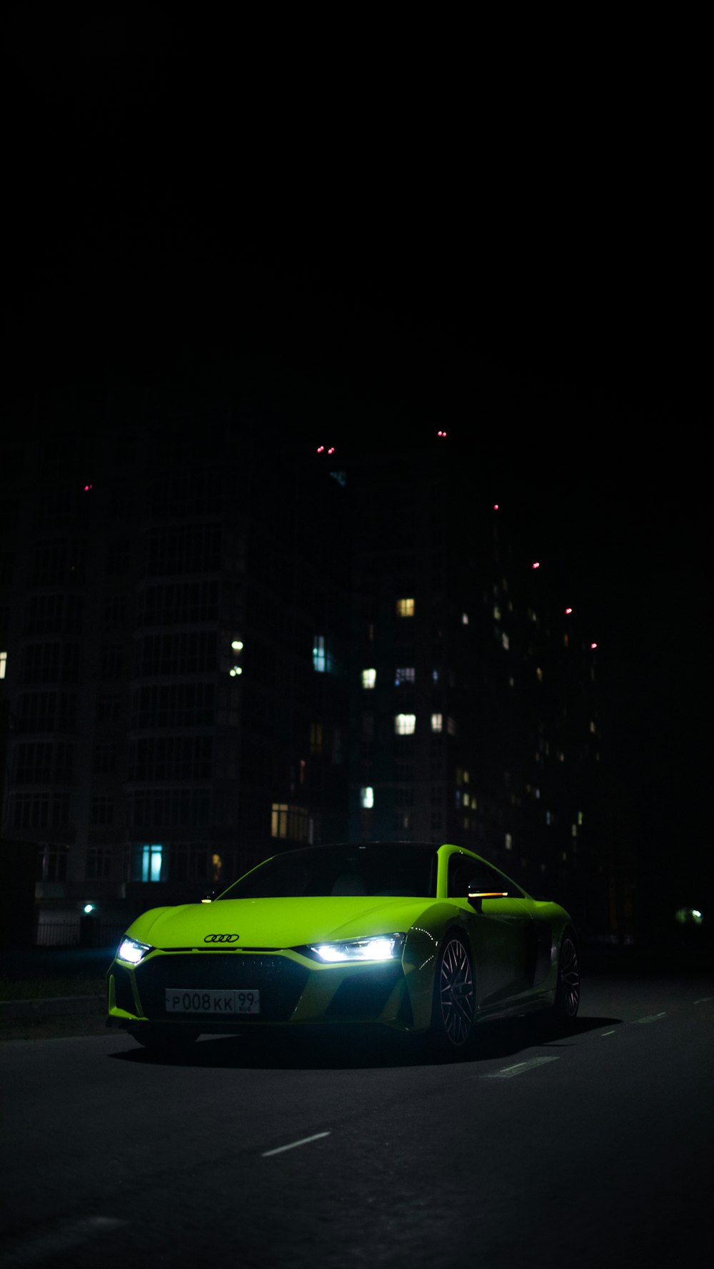 a green sports car driving down a street at night