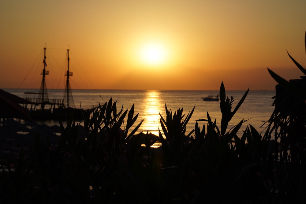 the sun is setting over the ocean with a boat in the distance