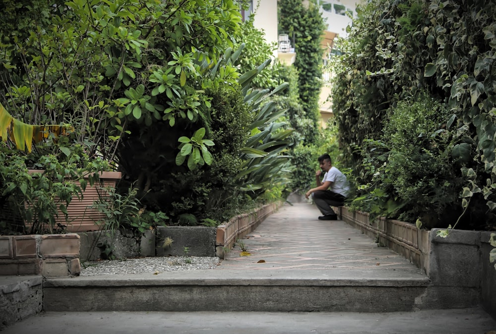 a man sitting on steps in the middle of a garden