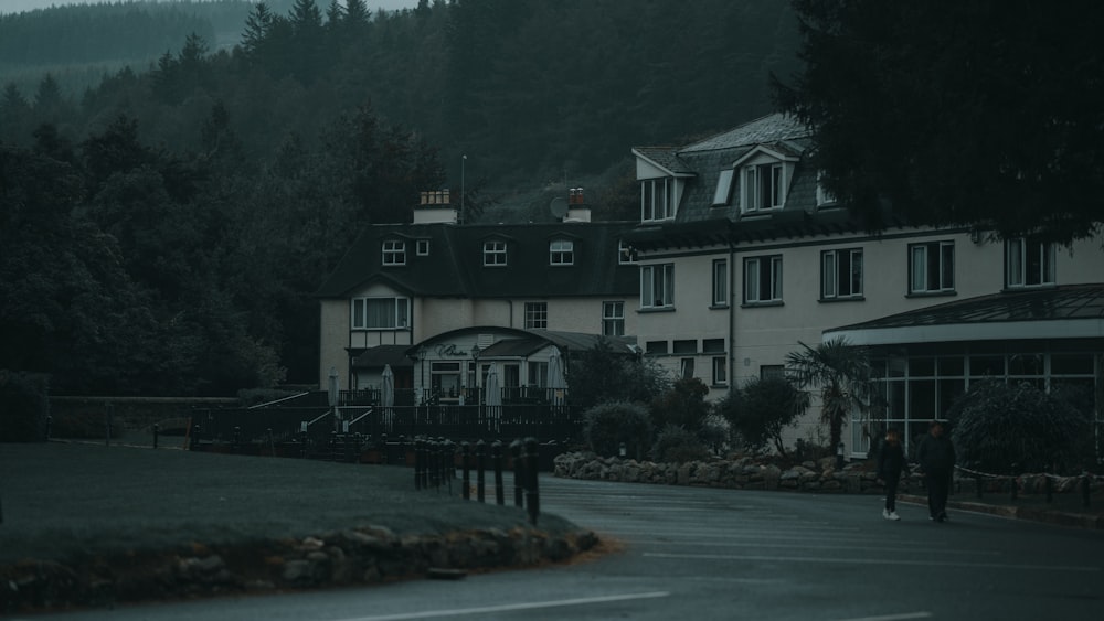 a person walking down a road in front of a large house