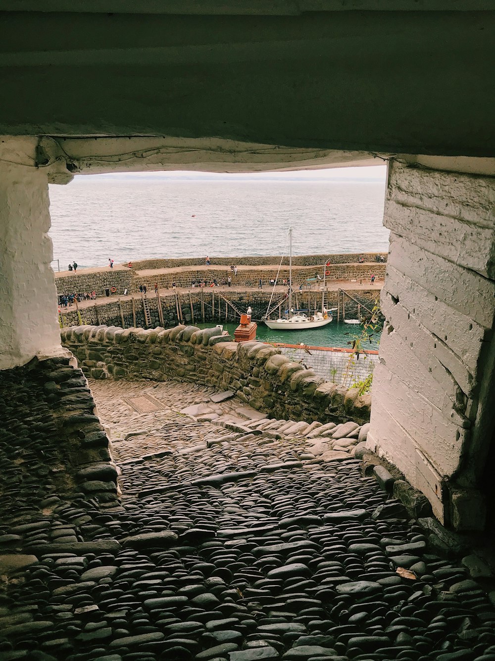 a stone walkway with a boat in the water