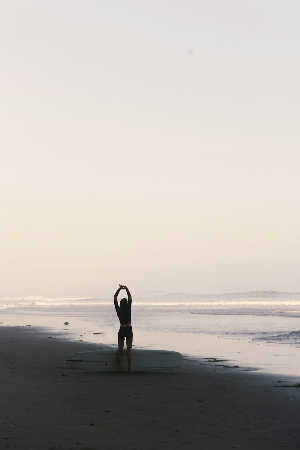 a person standing on a beach with a surfboard