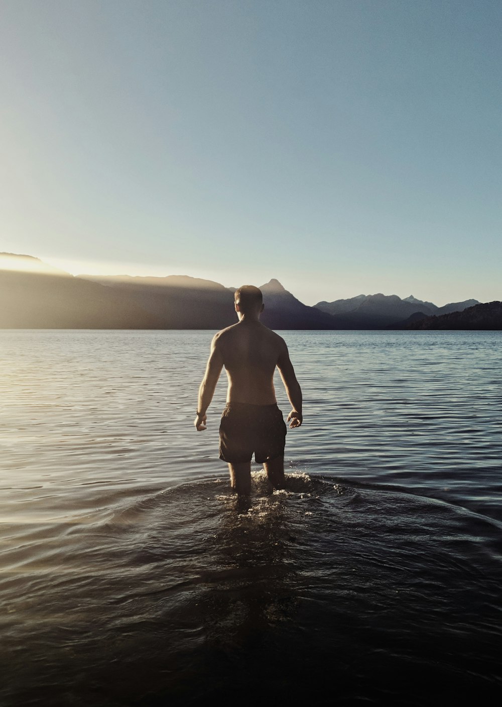 a man standing in the water with his back to the camera