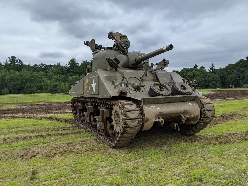 Un tanque militar sentado en la cima de un exuberante campo verde