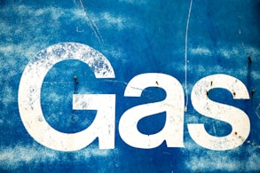 the word gas painted on the side of a blue wall
