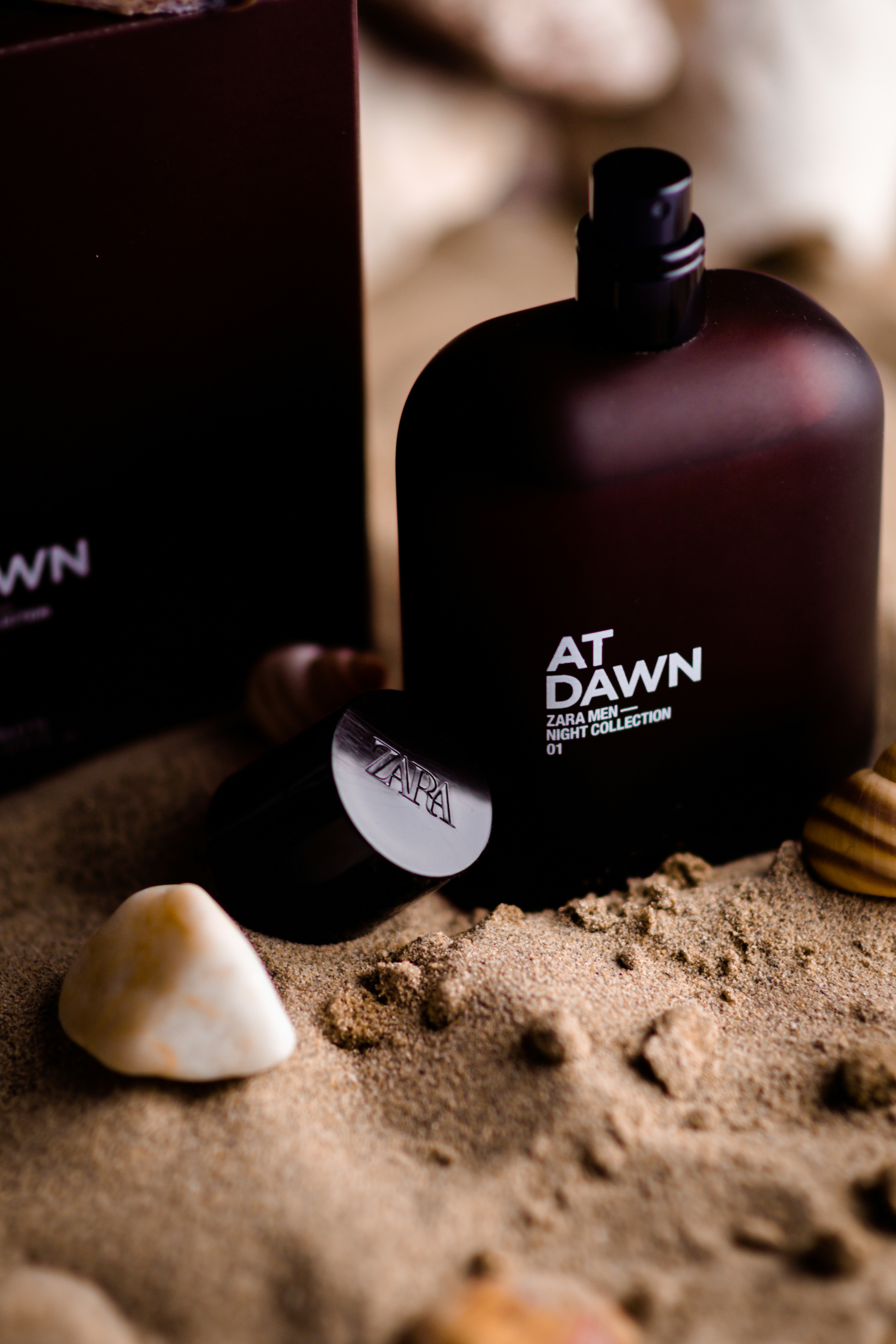 a close up of a bottle of perfume on a beach