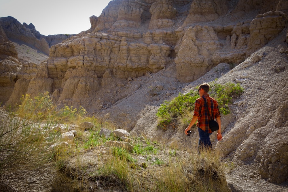 a man walking up a hill in the mountains