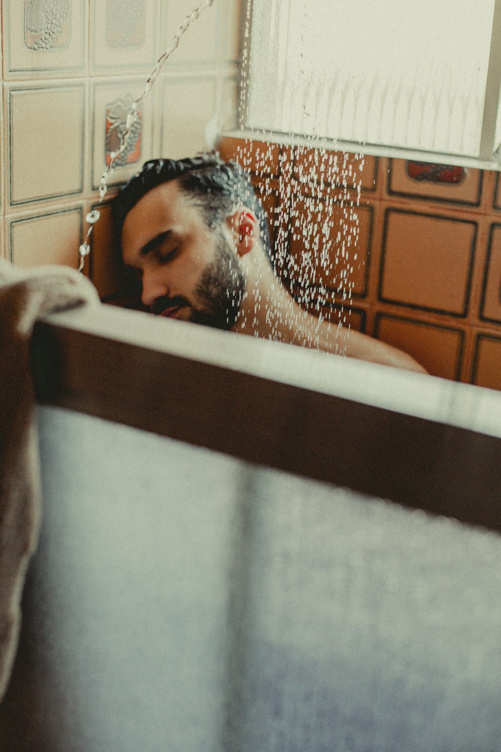 a man sitting in a bathtub with water coming out of his head