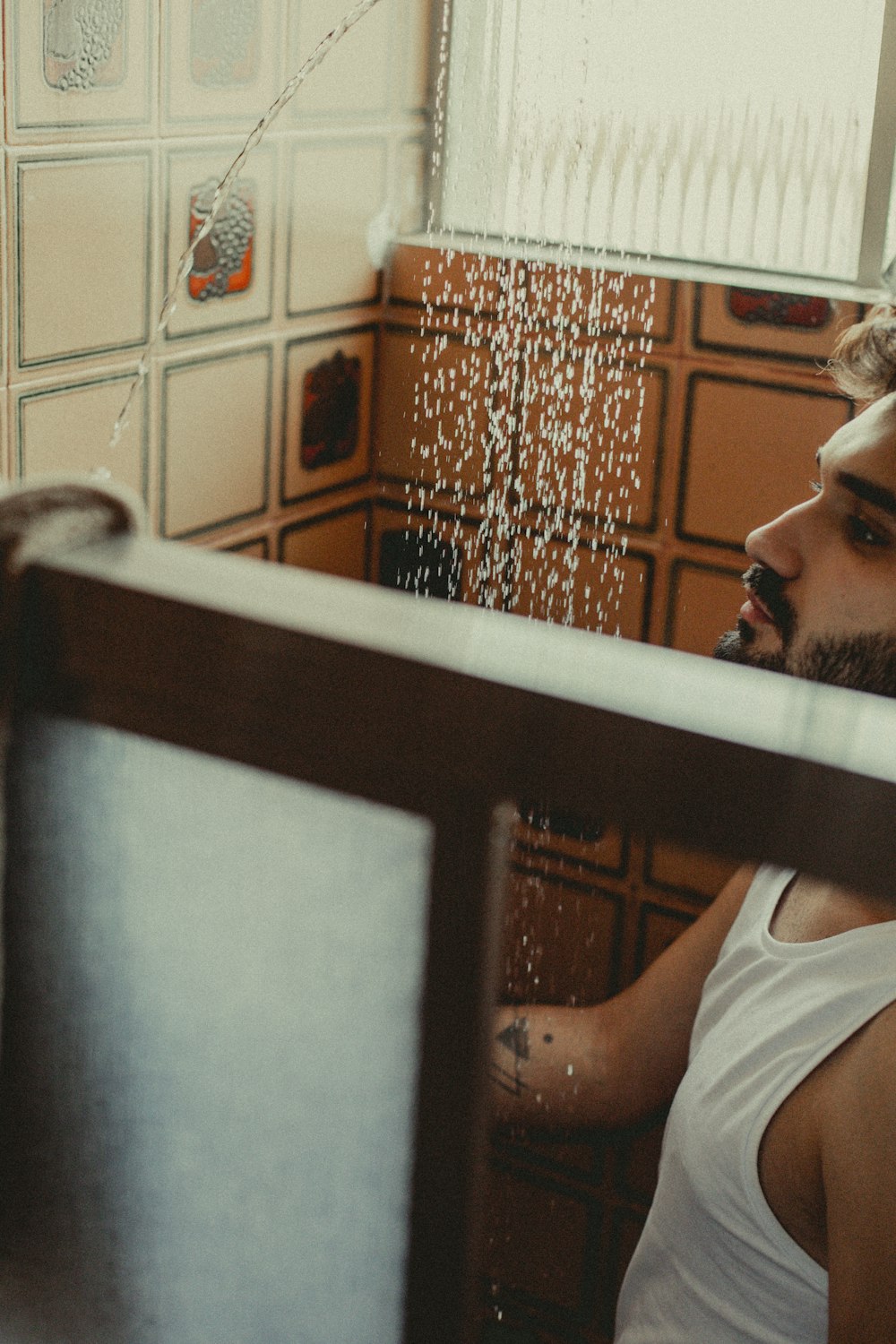 a man in a white tank top standing in front of a mirror