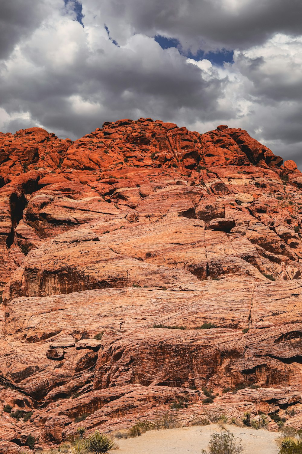 a large rock formation in the desert under a cloudy sky