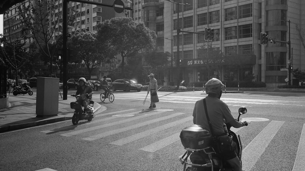 a man riding a motorcycle down a street next to tall buildings