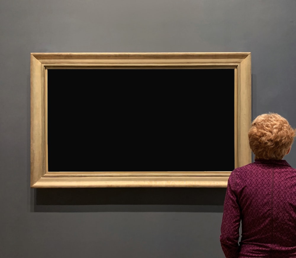 uma mulher olhando para uma pintura em uma parede