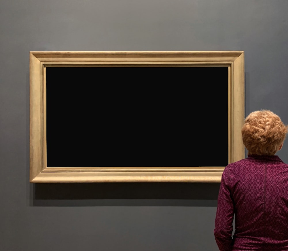 a woman looking at a painting on a wall