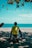a man sitting on a beach next to the ocean