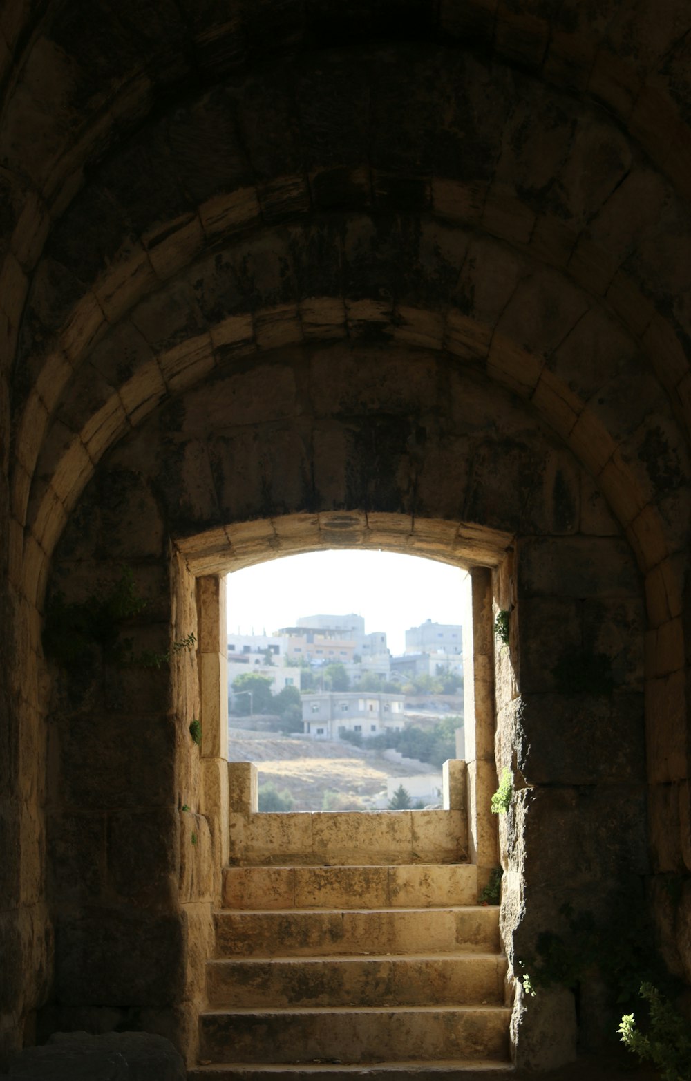 a stone archway with a view of a city through it