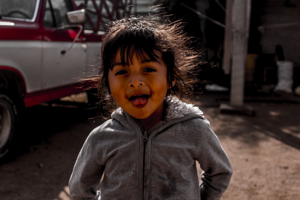 a little girl standing in front of a truck