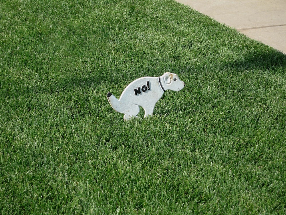 a white dog statue sitting on top of a lush green field