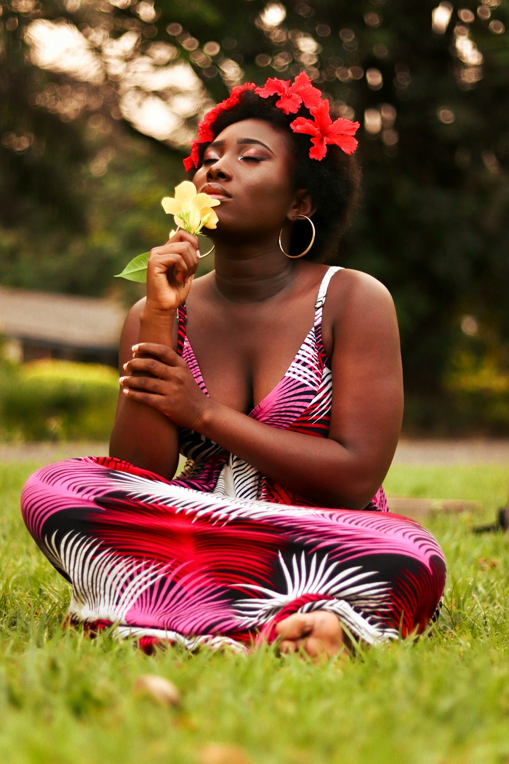 uma mulher sentada na grama com uma flor na boca