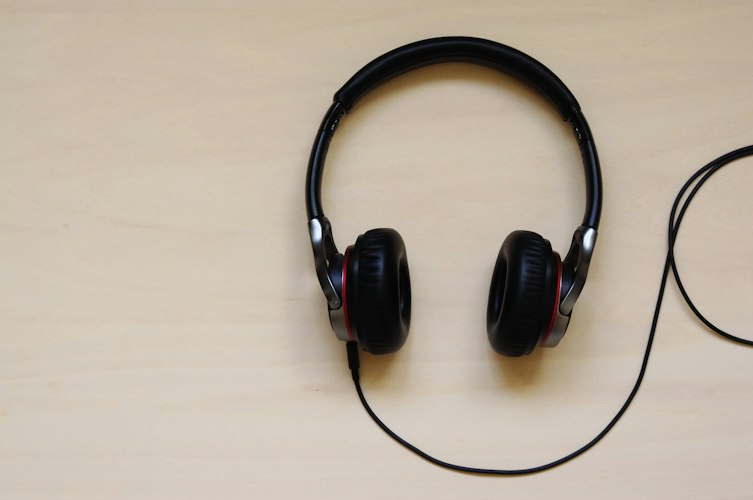 Black over-ear headphones lying flat on a light wooden table
