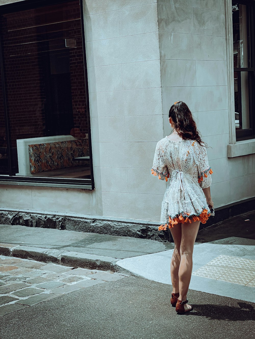 a woman walking down a street next to a tall building