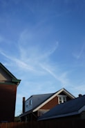 A freshly completed blue shingle roof on a suburban home under a clear sky