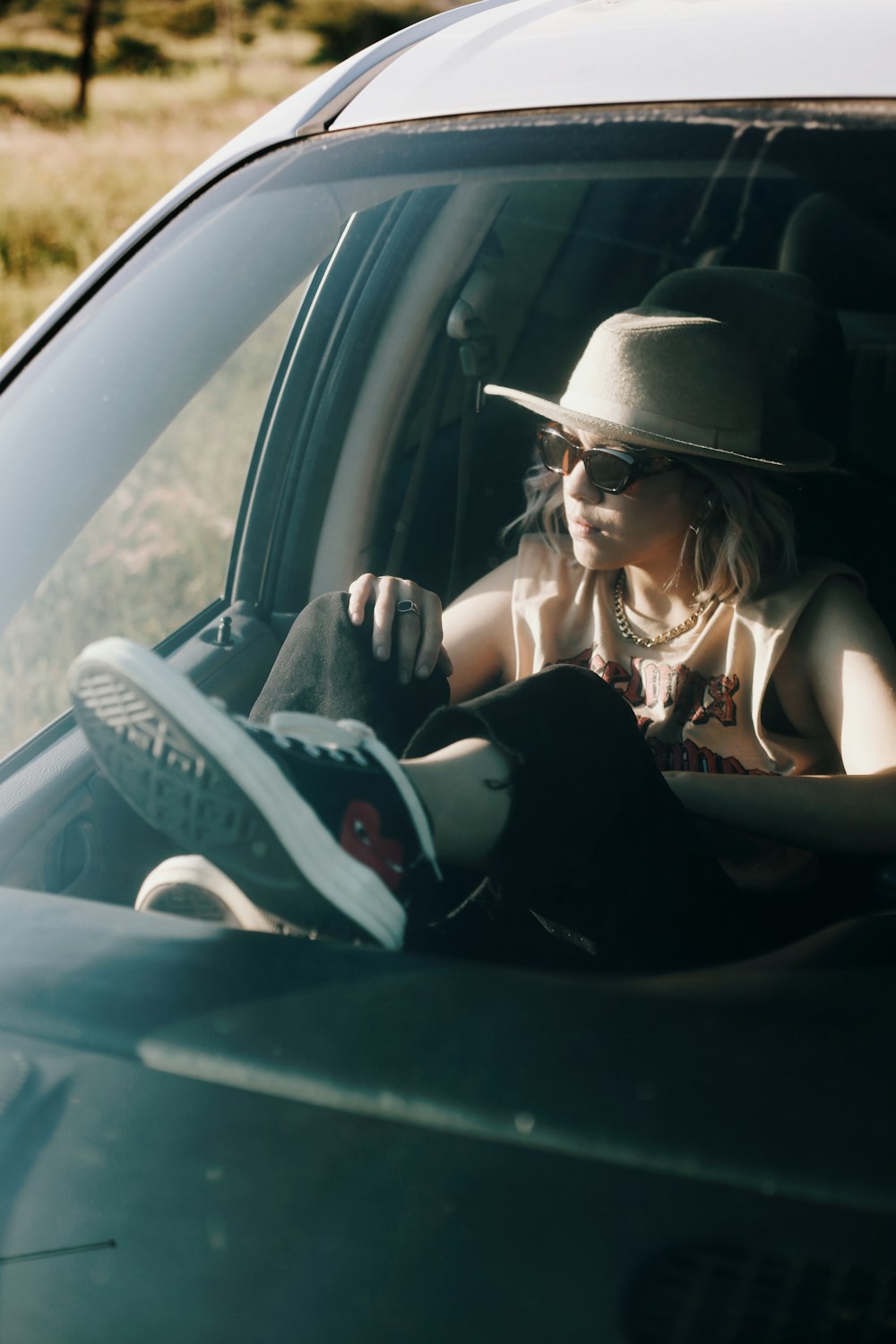 a woman sitting in a car with a hat on