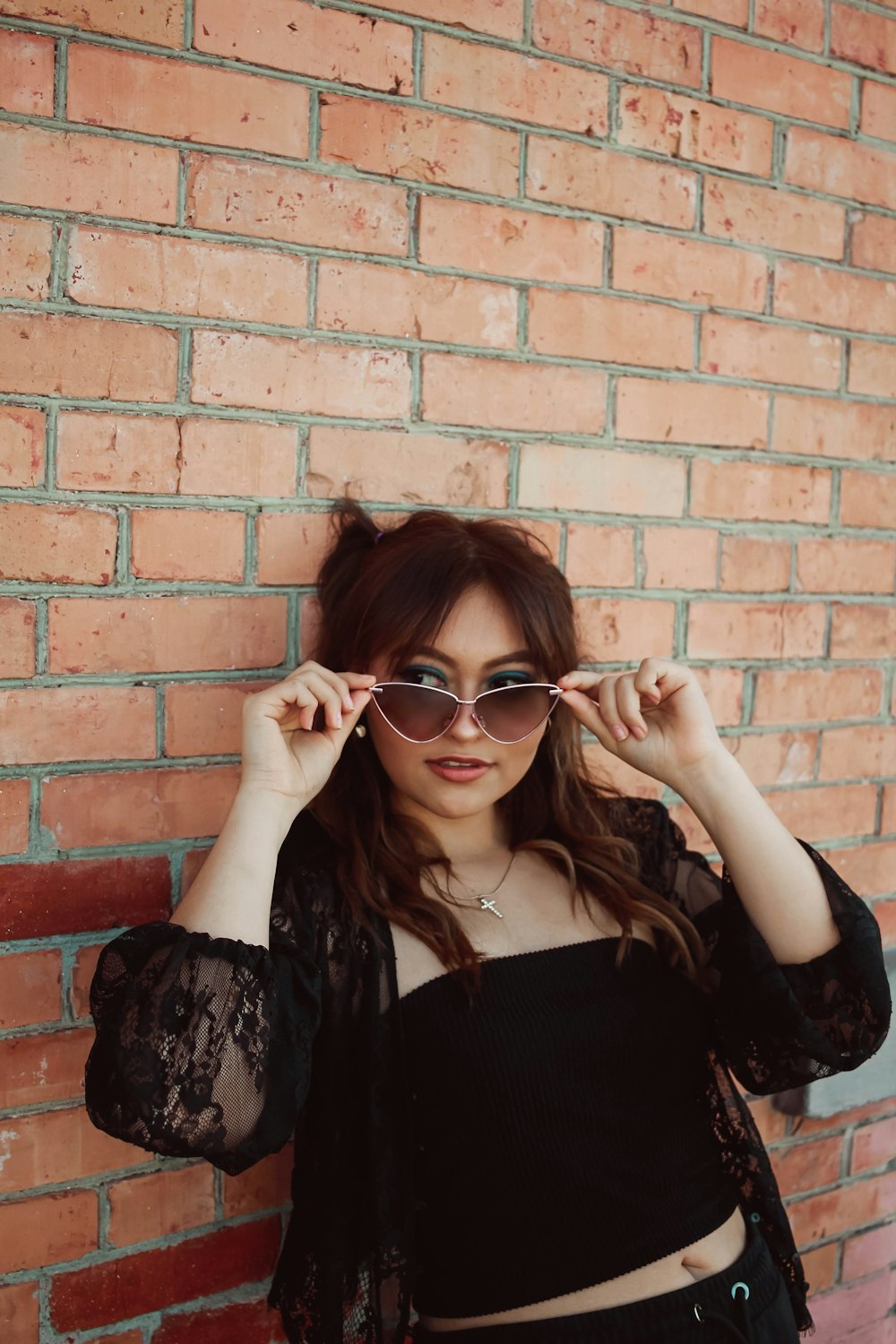 a woman in a black top is holding her glasses