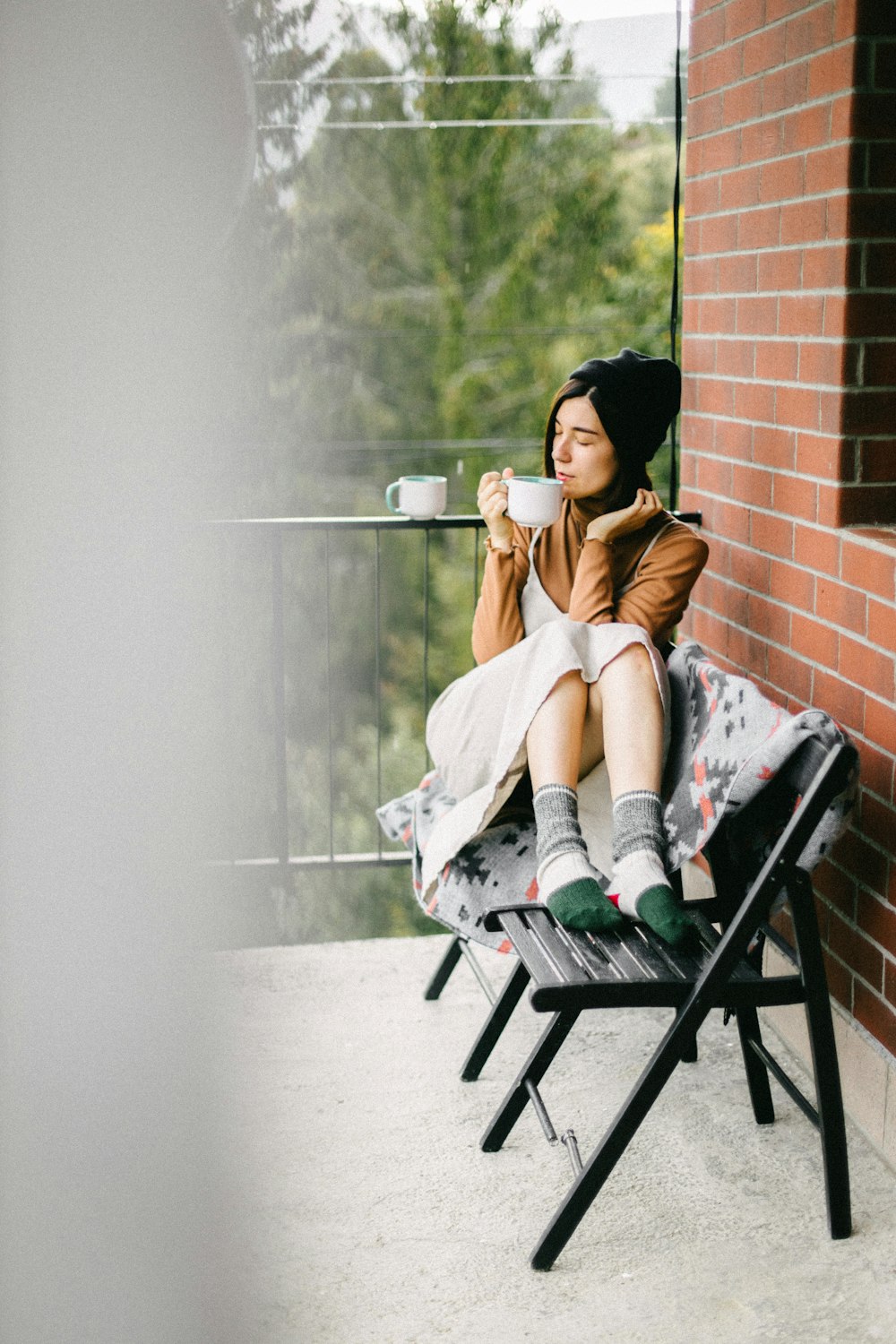 a woman sitting on a chair drinking a cup of coffee