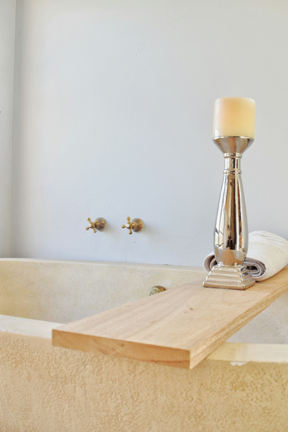 a candle is sitting on a piece of wood in a bathtub