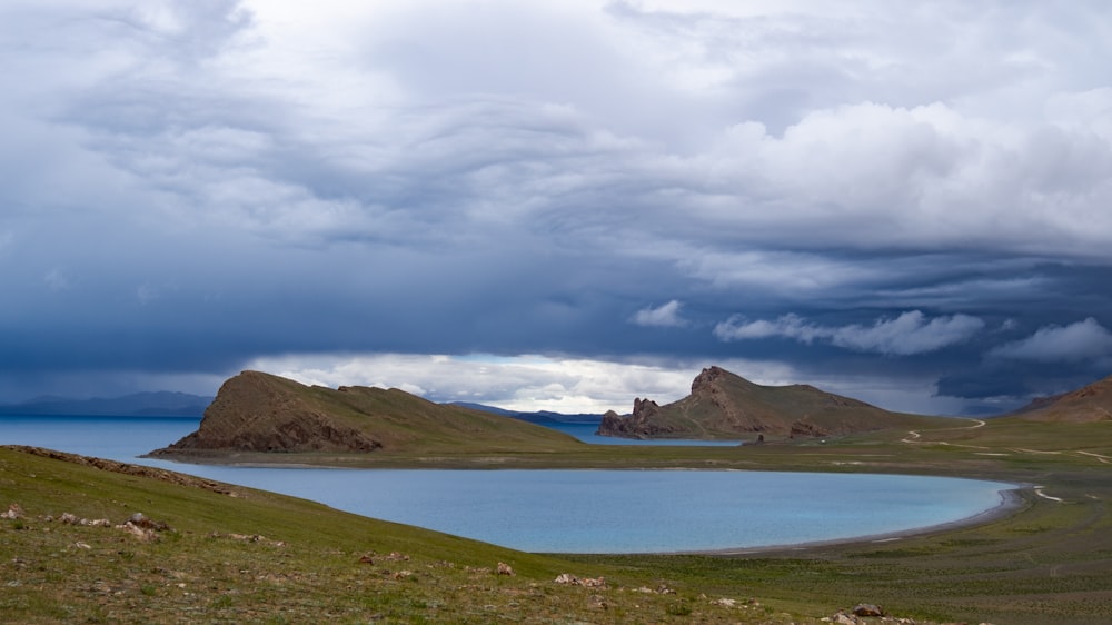 a body of water surrounded by mountains under a cloudy sky