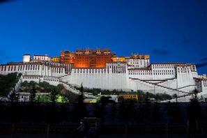 Exterior view of the palace at dusk, glowing softly against the evening sky